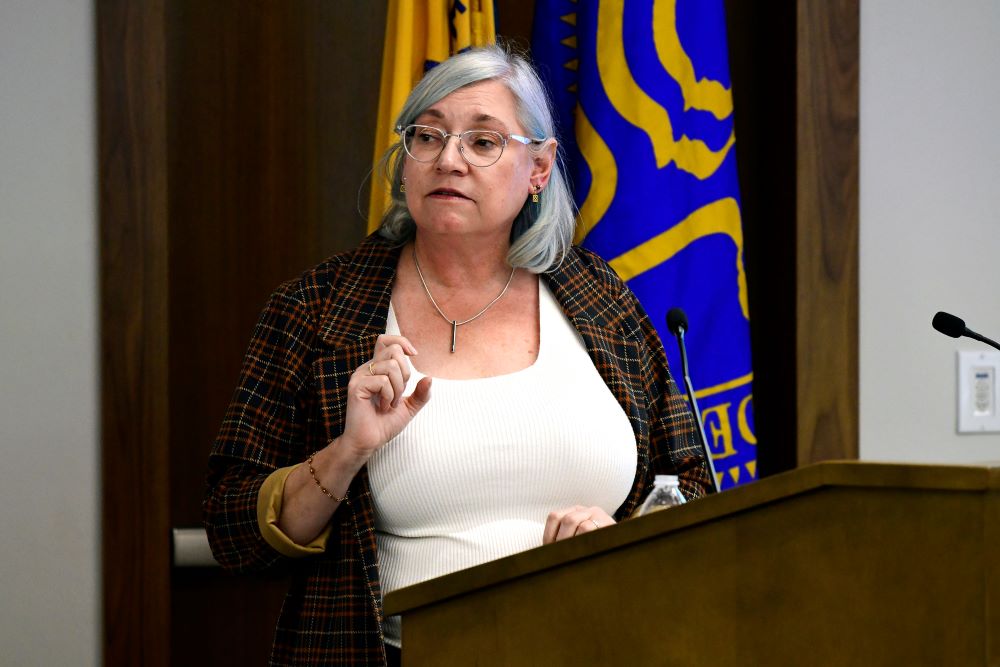 Dr. Susan Gregurick stands at a podium giving a talk at NIEHS.