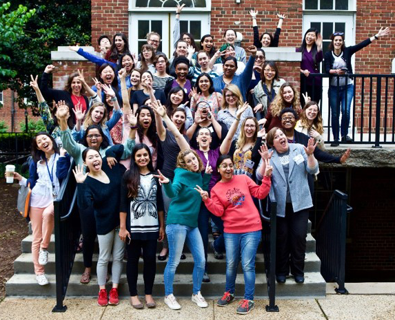 happy women of various ethnicities gathered on steps waving to the camera